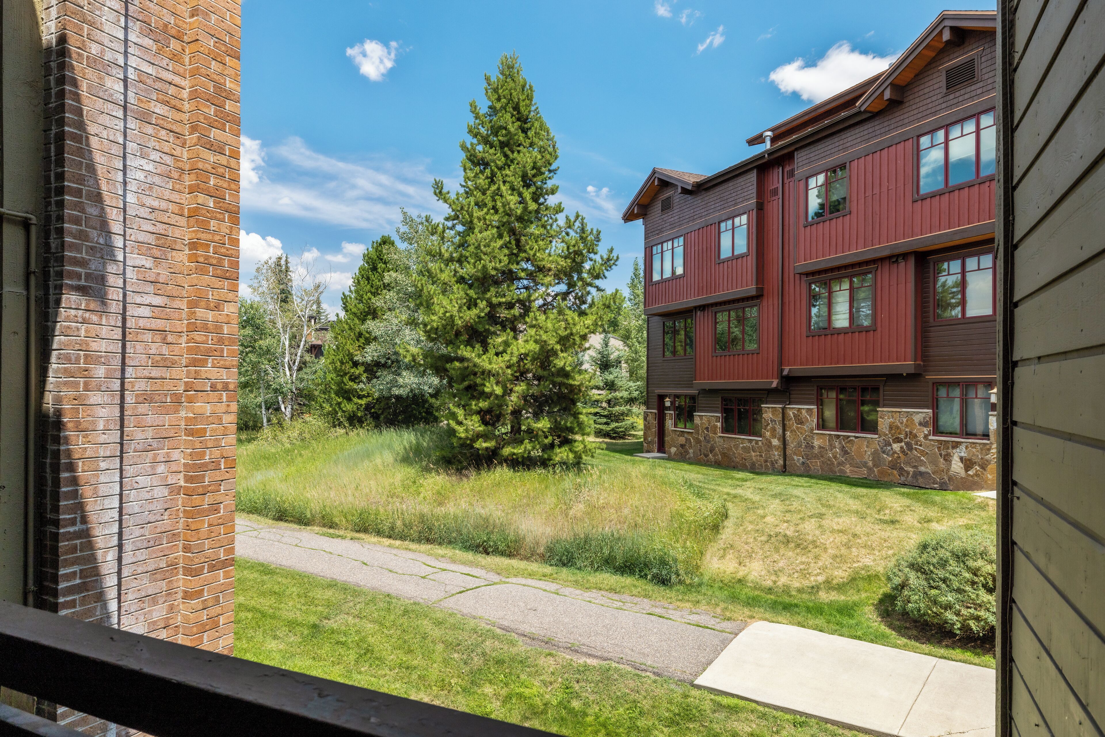 Un immeuble à étages doté d’une façade en briques, de quelques éléments décoratifs en pierre et d’une pelouse bien entretenue avec un grand arbre.