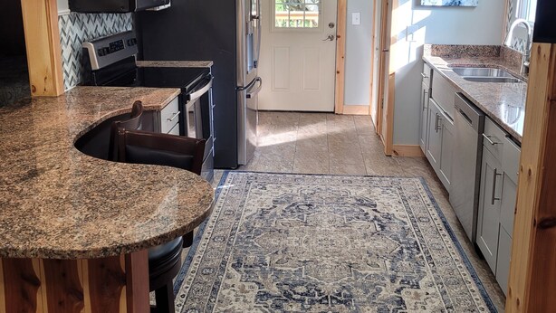 A kitchen with a granite countertop, a built-in microwave, a refrigerator, and a wooden bar area. - Cozy cottage condo with easy access to TIEC, Hendersonville, Asheville & Boone (Rutherfordton)