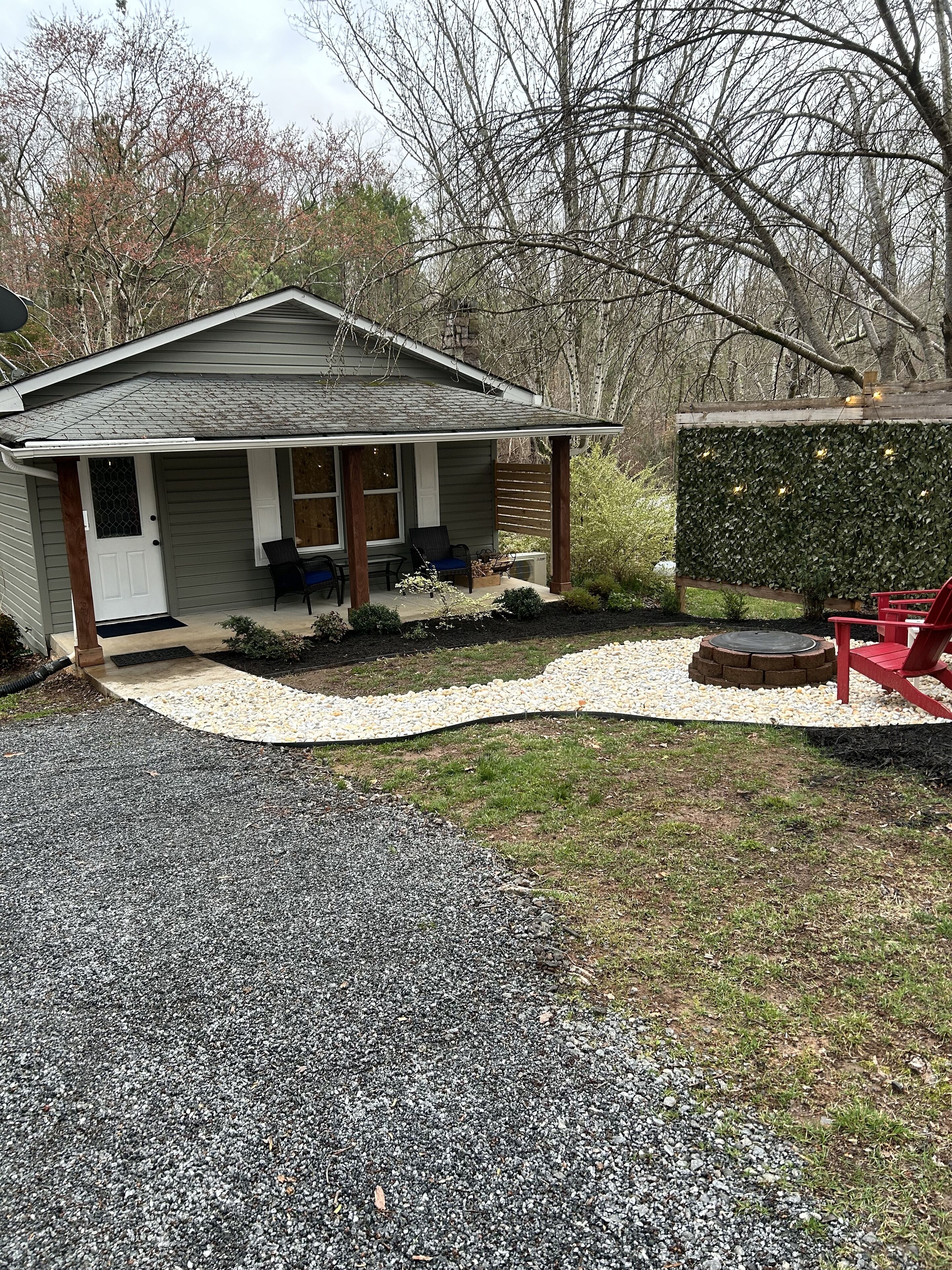 A house with a porch, a small garden area with a gravel path, and a red chair.