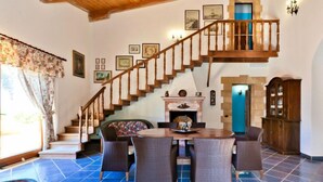 A spacious living area with a high wooden staircase, a fireplace, and a dining table set for four. - Le Palme by Interhome (Valderice)