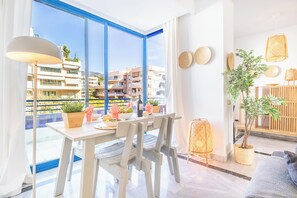 Un salon moderne avec un coin repas, de grandes fenêtres et une vue sur le paysage urbain.