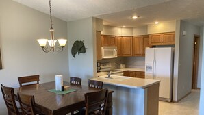 A modern kitchen with wooden cabinets, a central island with a sink, and a refrigerator. - Hunting, Fishing and River-fun Getaway! (Pierre)