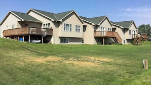 A row of two-story houses with attached decks and a grassy yard. - Hunting, Fishing and River-fun Getaway! (Pierre)