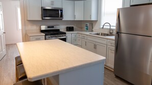 Une cuisine moderne avec des armoires blanches, des appareils en acier inoxydable et un plan de travail de couleur claire.