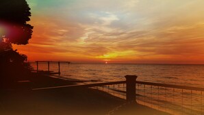 Une vue sur le coucher de soleil depuis une jetée dotée d’une rambarde, avec la mer en contrebas.