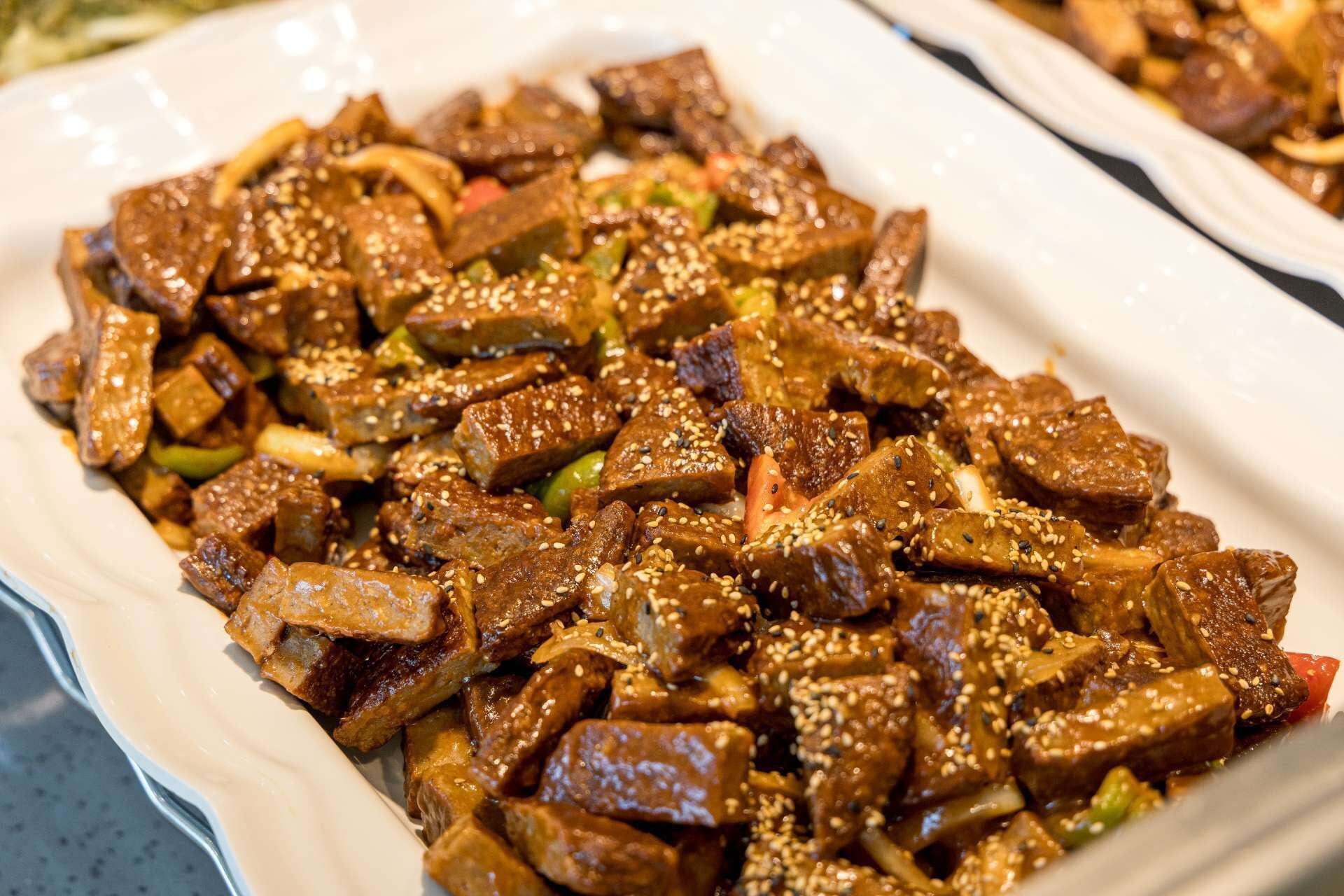 A dish of stir-fried meat with vegetables and sesame seeds.