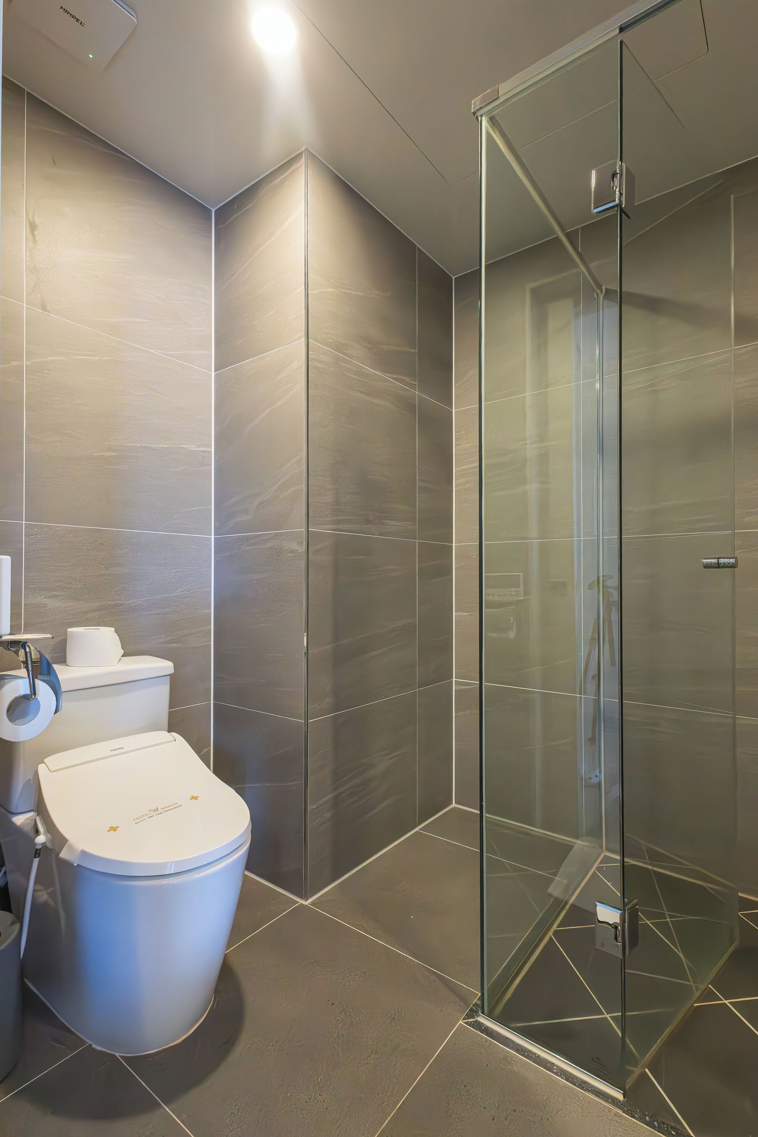 A modern bathroom with a glass-enclosed shower, a toilet, and a bidet.