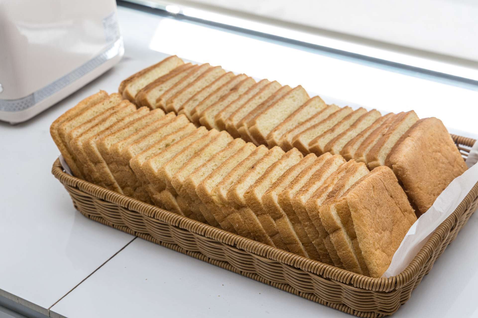 Ein Korbkörbchen mit ordentlich angeordneten Brotscheiben.