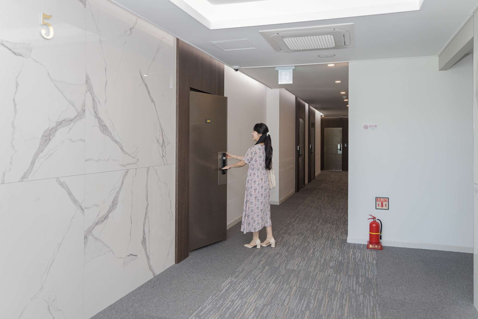 A woman entering a hotel room through a door marked with the number 501.