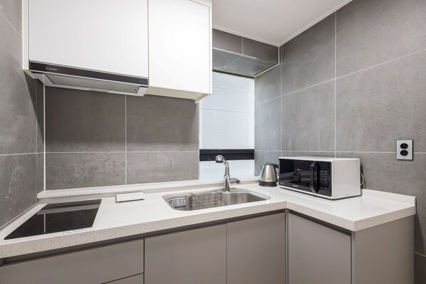 A modern kitchen with a built-in microwave, stainless steel sink, and a ventilation hood.