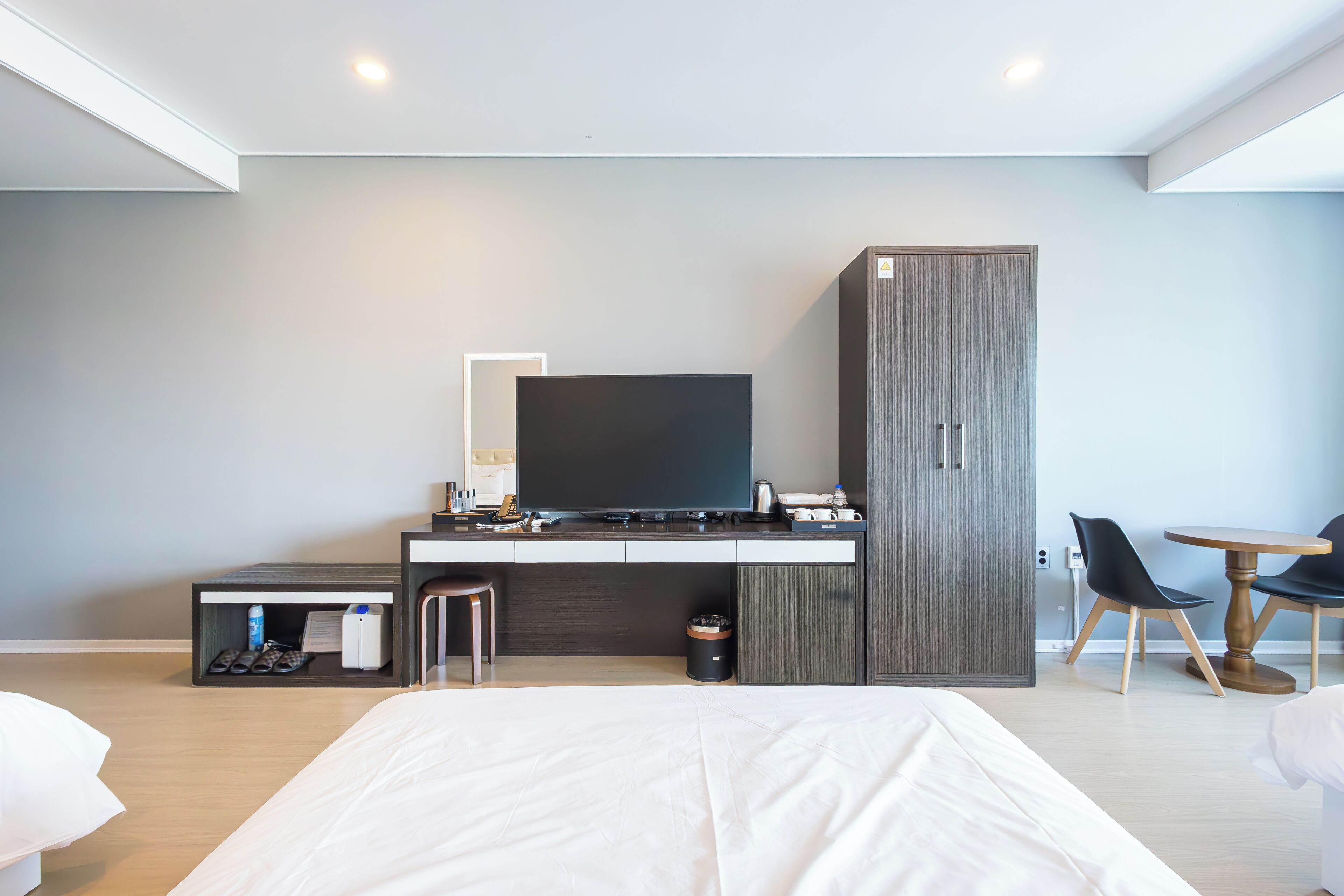 Een moderne hotelkamer met een groot bed, een flatscreen televisie, een bureau met stoel, een kledingkast en een klein eettafeltje met stoelen.