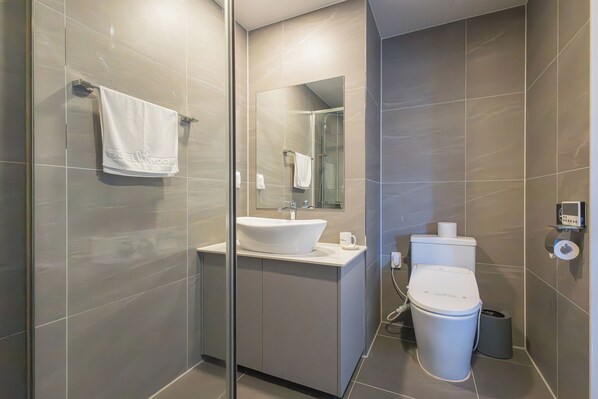 A modern bathroom with a glass shower enclosure, a white sink, and a toilet. - Hotel Wooin (Mokpo)