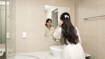 A modern bathroom with a large mirror, a white sink, and a glass shower enclosure.