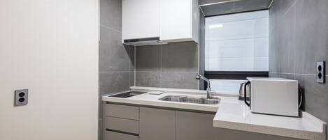 Una cocina moderna con horno empotrado, lavaplatos y microondas.