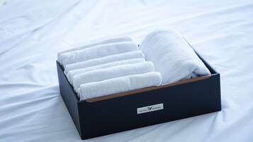 Eine schwarze Box mit Holzbasis, gefüllt mit sauber gefalteten weißen Handtüchern, beschriftet mit „HOTEL WOIN“.