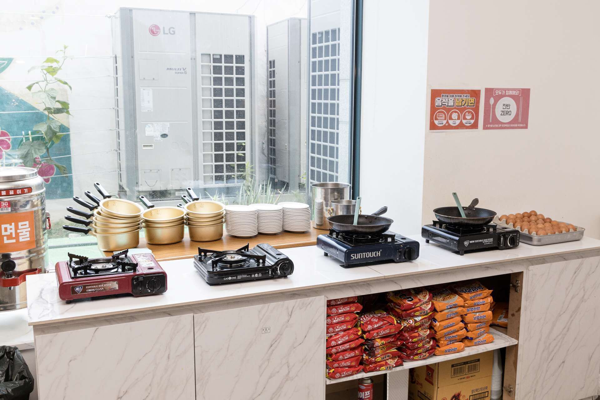 A kitchen area with cooking utensils, a portable gas stove, and packaged food items.