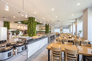 A modern restaurant with a central island, seating area, and indoor plants.