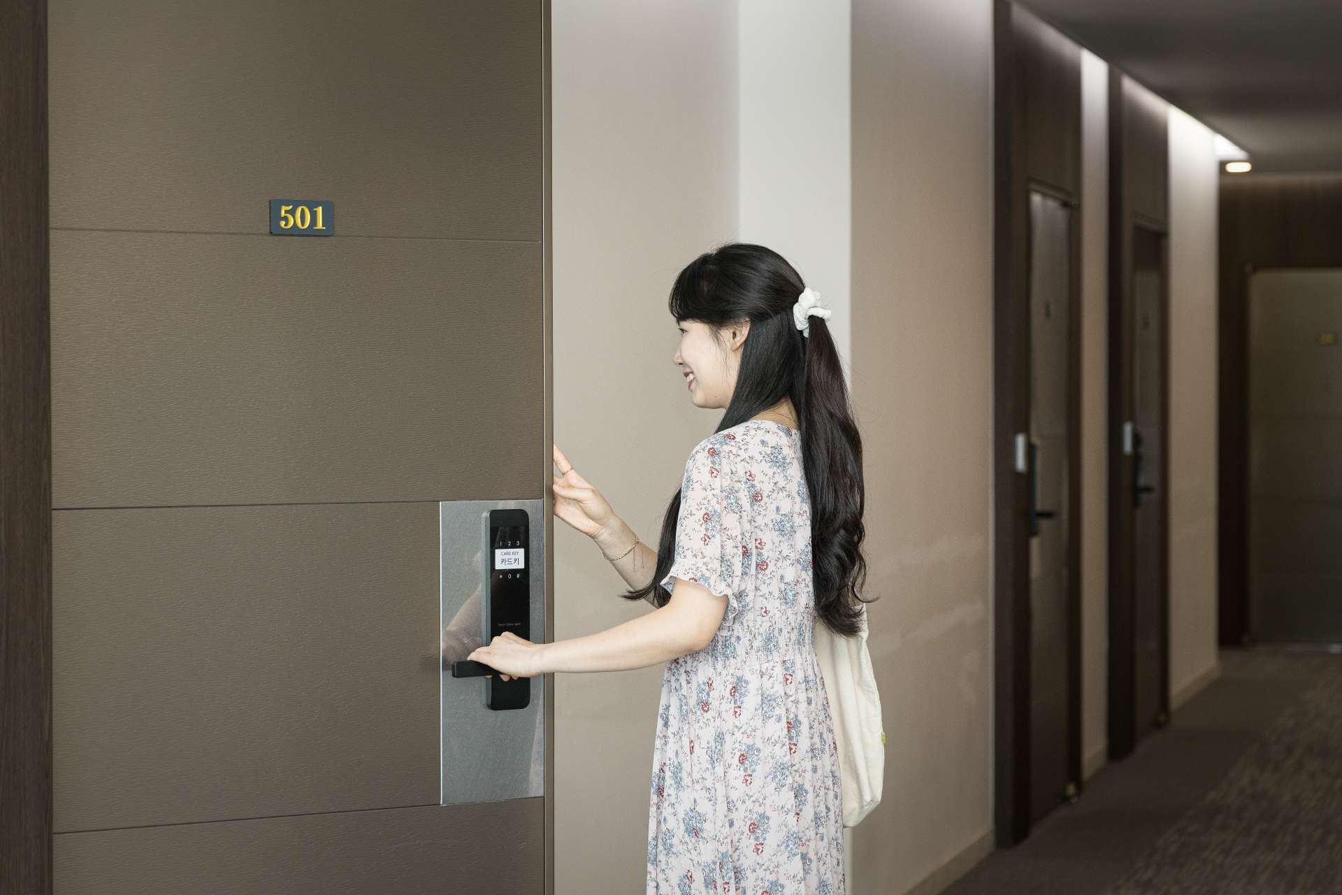 A person using a card key entry system in a hallway with doors and a sign indicating room number 501.