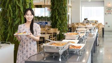 A buffet setup with multiple serving stations, a person holding a plate, and a modern interior with plants and seating areas.