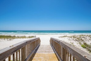 Un muelle de madera que conduce a una playa arenosa con vistas al océano.