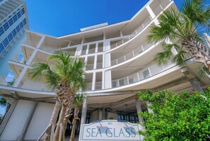 Ein mehrstöckiges Hotel mit Balkonen, Palmen und einem Schild mit der Aufschrift 'SEA GLASS'.