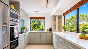 Eine moderne Küche mit Einbauofen, Spüle und einem Fenster mit Blick auf Grünflächen.