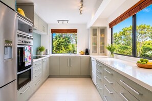 Una cucina moderna con forno a incasso, lavello e finestra vista verde.