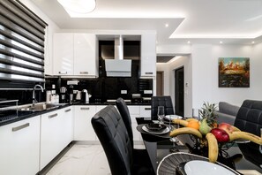 Una cocina moderna con zona de comedor, con una decoración en blanco y negro, una isla central y un frutero sobre la mesa.