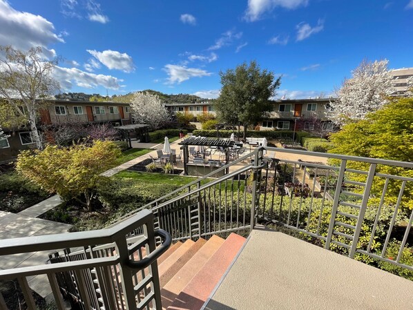 A courtyard with outdoor seating, a staircase, and a view of residential buildings.