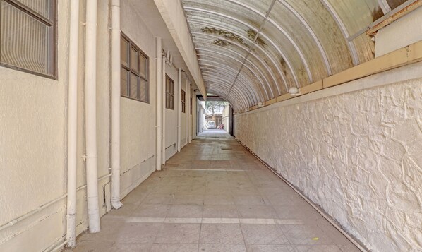 A long, narrow corridor with a high, arched ceiling and white walls.
