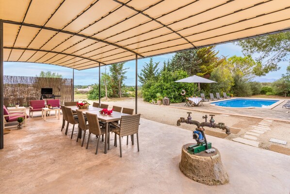 Une terrasse extérieure avec une table et des chaises, un barbecue, une piscine et un élément décoratif aquatique.