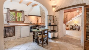 A kitchen with a dining table, chairs, a sink, and a staircase leading to another level.