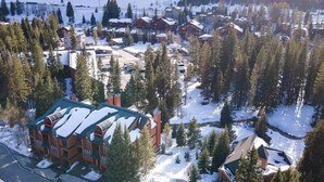 Een besneeuwd dorp met traditionele houten huizen, omgeven door dichte bossen en bergen.