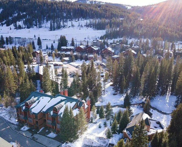 A snow-covered village with traditional wooden houses, surrounded by dense forests and mountains. - Beautiful Condo - Riverfront-Slopeside-Walk to Resort-On Bus Route (Winter Park)
