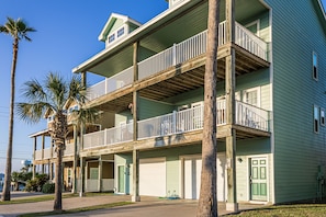 A multi-story building with balconies, a green door, and a visible water tank.