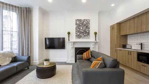 A modern living room with a grey sofa, a round coffee table, and a fireplace.