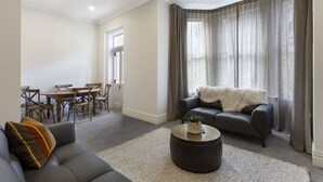 A modern living room with a sofa, a coffee table, and a dining area with chairs and a table.