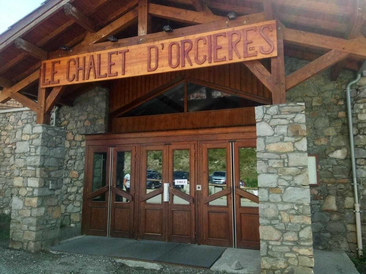 A wooden entrance with a sign reading "LE CHALET D'ORCIERES".