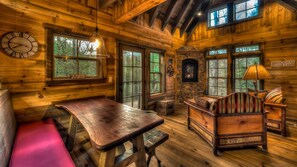 Cozy cabin interior with a large wooden table, comfortable sofa, and stone fireplace.