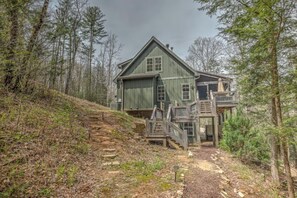 A large, green wooden house with a steep driveway and a wooden deck. - Escape to Water Dance - Riverfront Fire Pit | Hot Tub | Foosball (Blue Ridge)