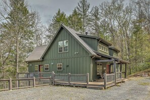 A green wooden cabin with a porch, surrounded by trees. - Escape to Water Dance - Riverfront Fire Pit | Hot Tub | Foosball (Blue Ridge)