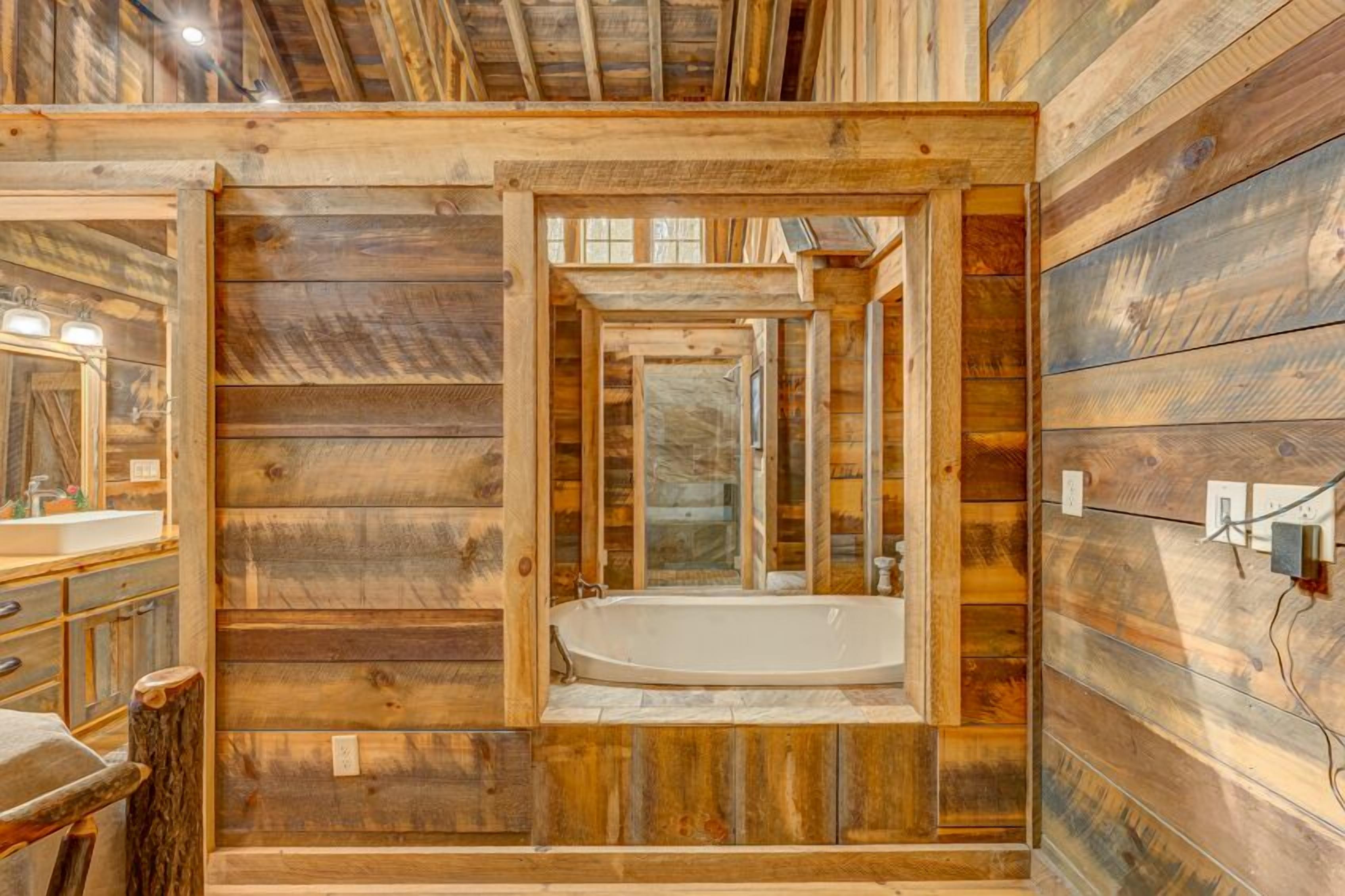 Une salle de bain rustique en bois, avec une baignoire sur pieds, des murs en bois et un miroir.