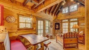 Ein gemütliches Blockhaus-Interieur mit einem Holzesstisch, Bänken und einem Kamin.