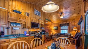 A wooden cabin interior with a kitchen, dining area, and living room. - Niboban Cabin 5 right on Rangeley Lake with a screened porch, fire pit, hammock, WiFi and dock! (Rangeley)