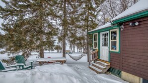 A wooden cabin with a porch, a hammock, and a snow-covered deck. - Niboban Cabin 5 right on Rangeley Lake with a screened porch, fire pit, hammock, WiFi and dock! (Rangeley)