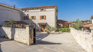 A stone building with a tiled roof, a wooden door, and a small garden area. - Renoviertes Istrisches Haus (Peresiji)