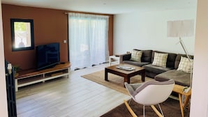A living room with a TV, sofa, coffee table, and a lamp.