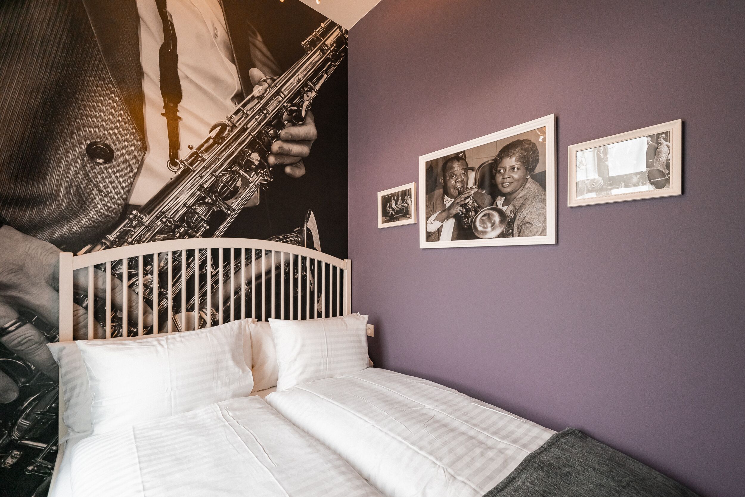 A bedroom with a bed, a headboard, and a wall with framed pictures.