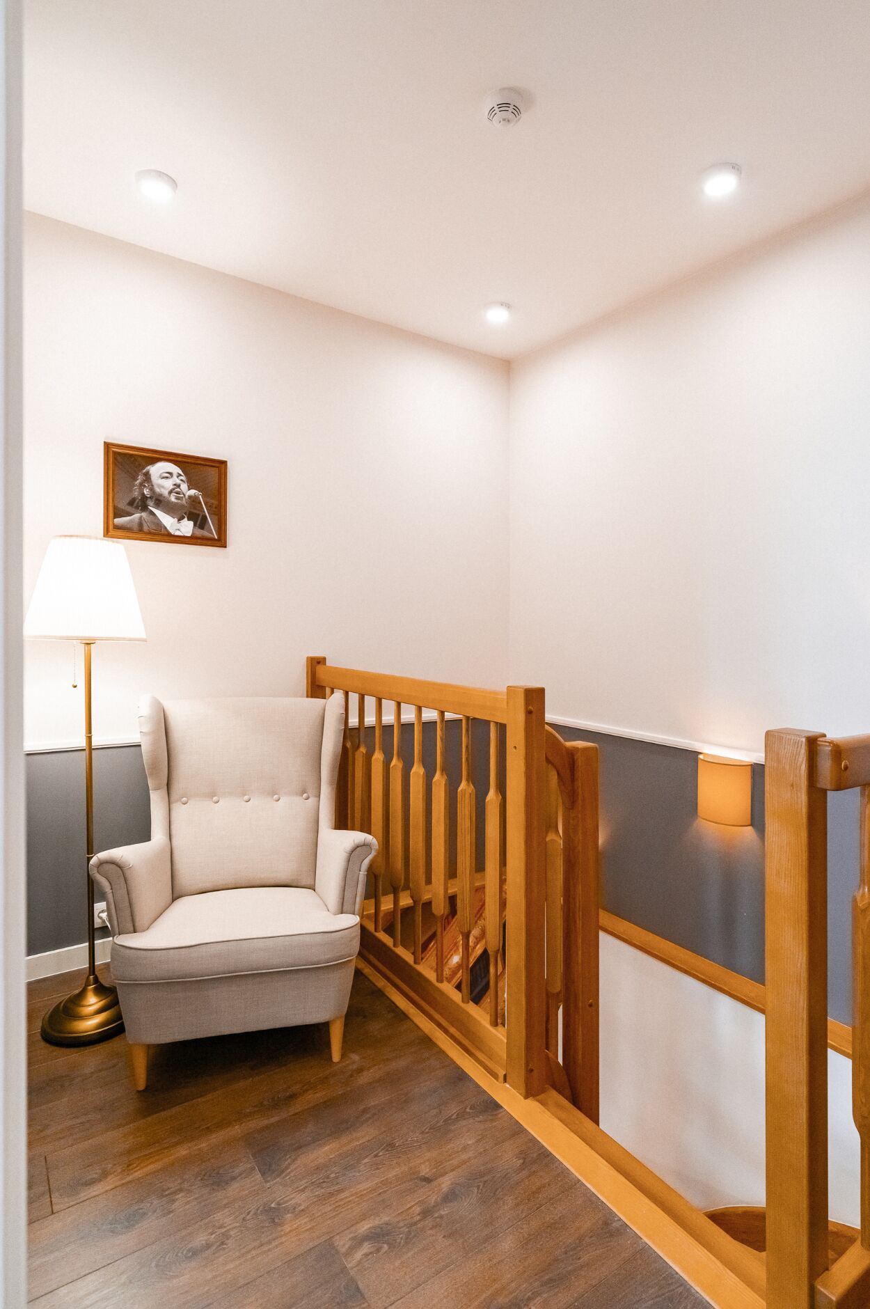 A room with a wooden chair, a floor lamp, and a picture on the wall.