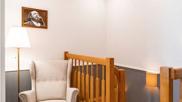 A room with a wooden chair, a floor lamp, and a picture on the wall.